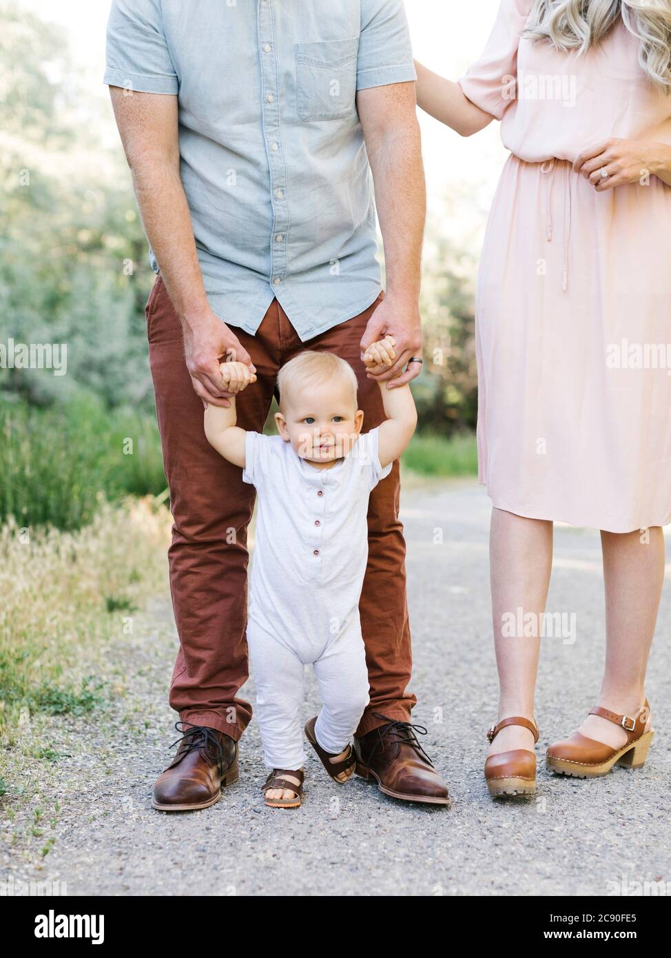 Les parents aident bébé fils à apprendre à marcher à l'extérieur Banque D'Images