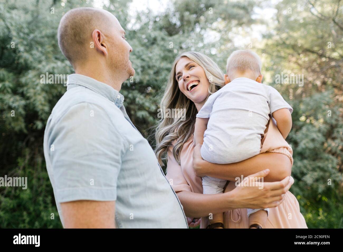 Parents heureux avec bébé fils riant dans le jardin Banque D'Images
