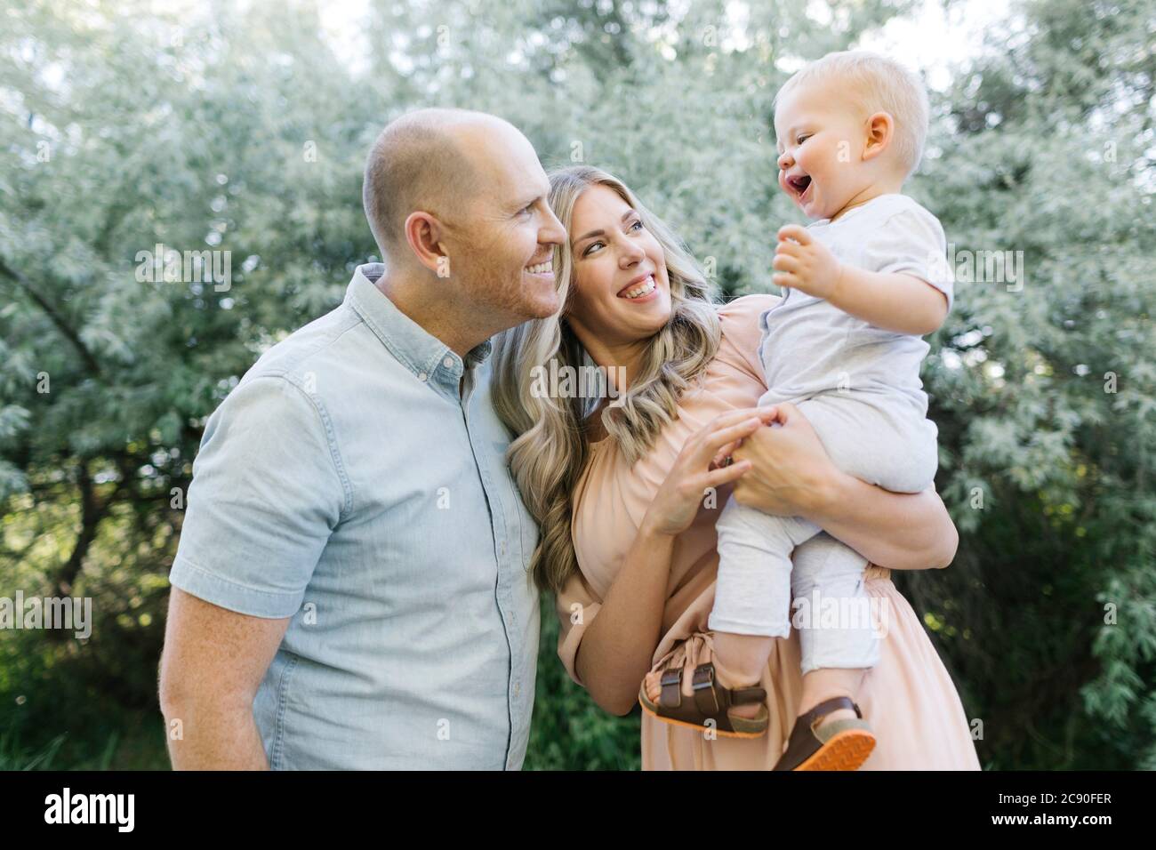 Parents heureux avec bébé fils riant dans le jardin Banque D'Images