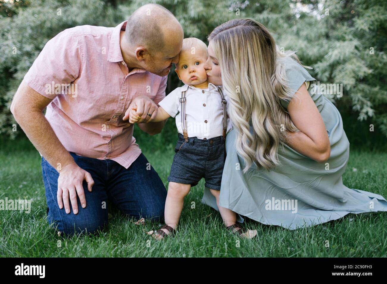 Parents embrassant bébé fils dans le jardin Banque D'Images