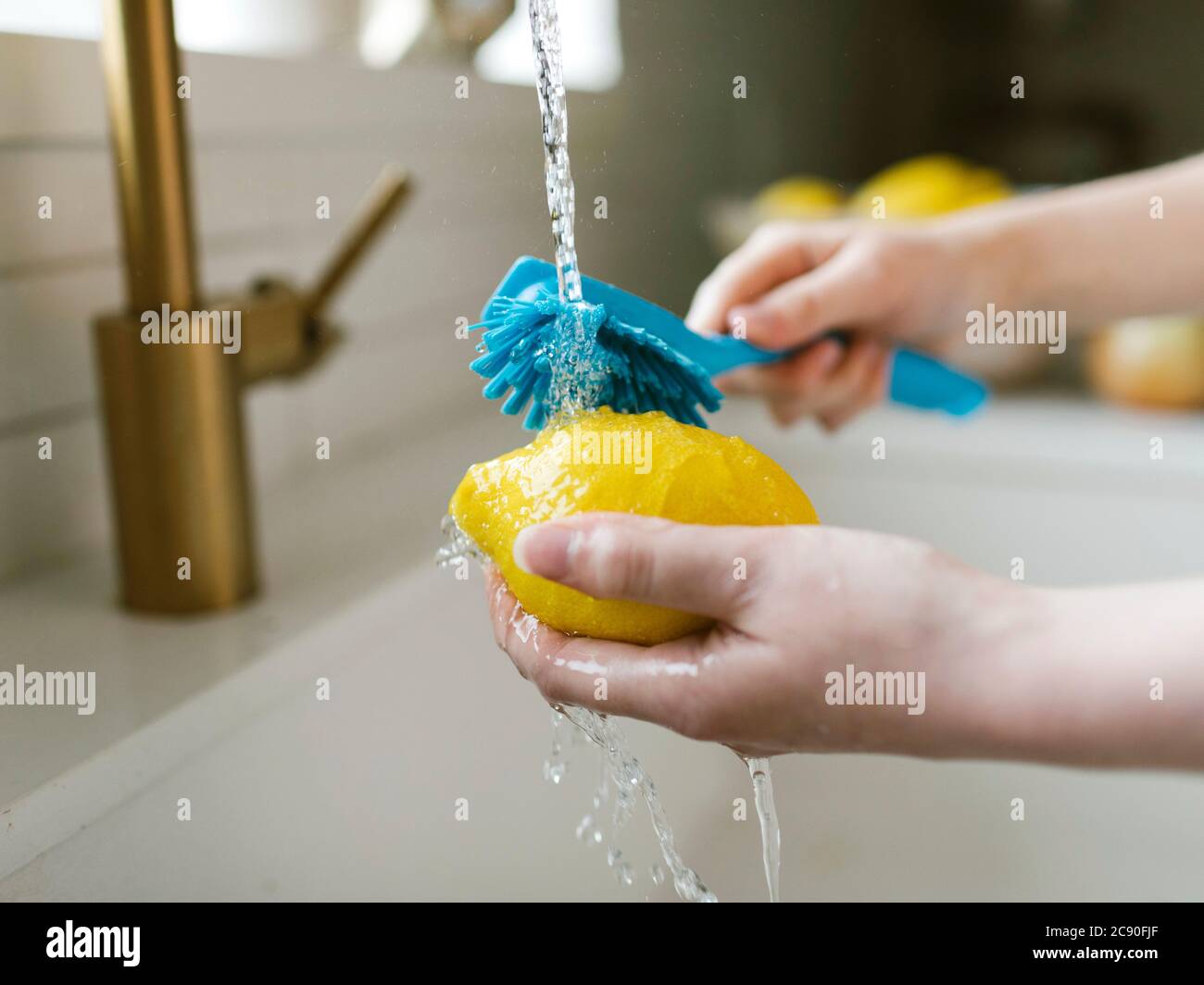 Femme lavant le citron avec la brosse Banque D'Images
