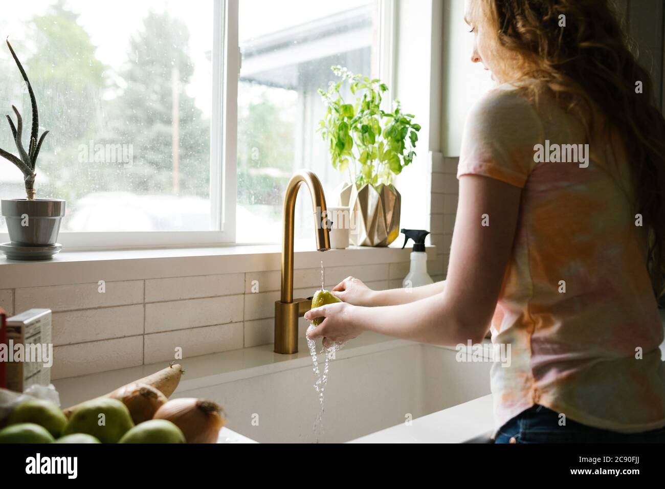 Femme lavant la poire dans la cuisine Banque D'Images