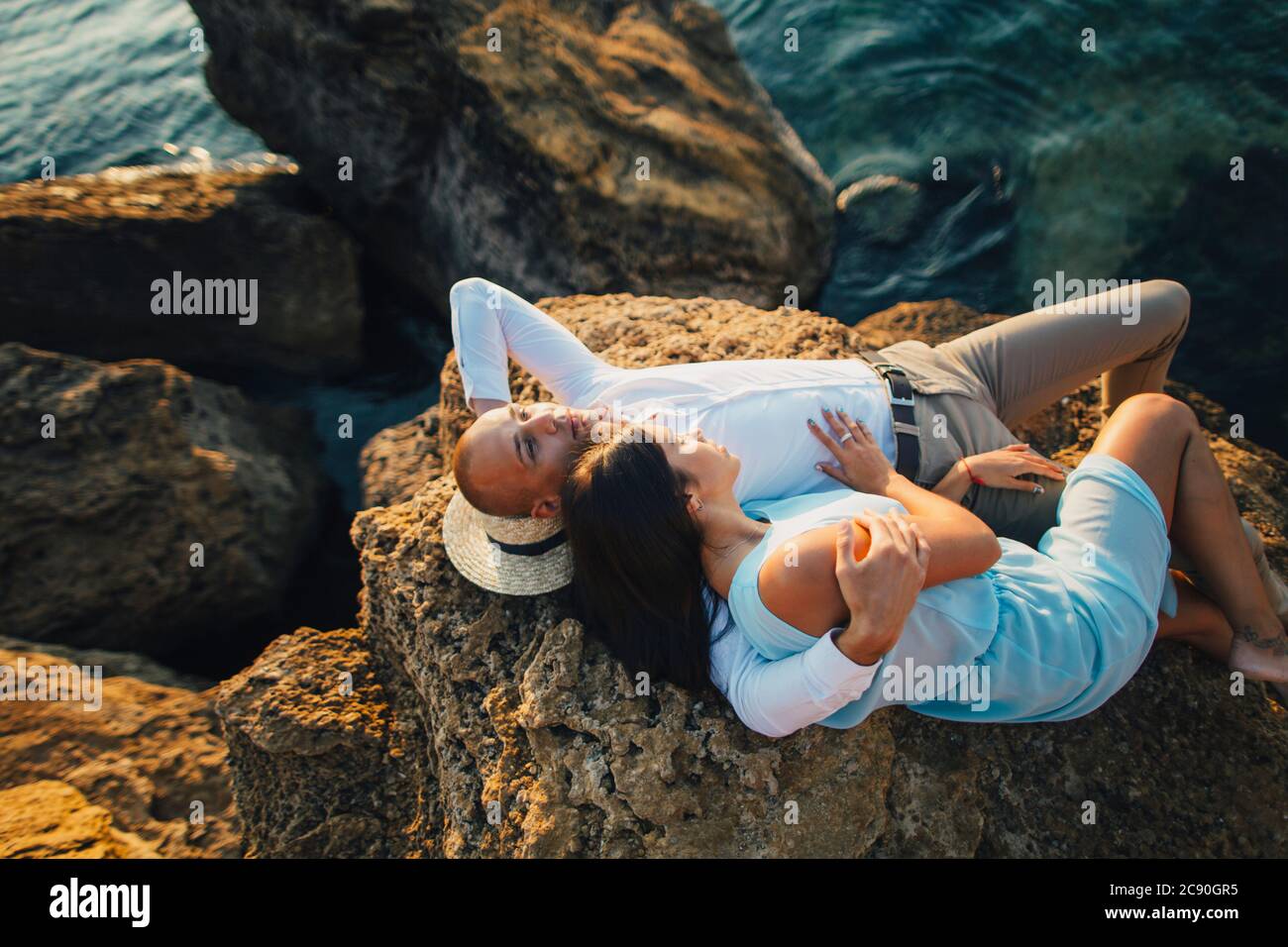 Couple romantique reposant sur le rocher au bord de la mer Banque D'Images