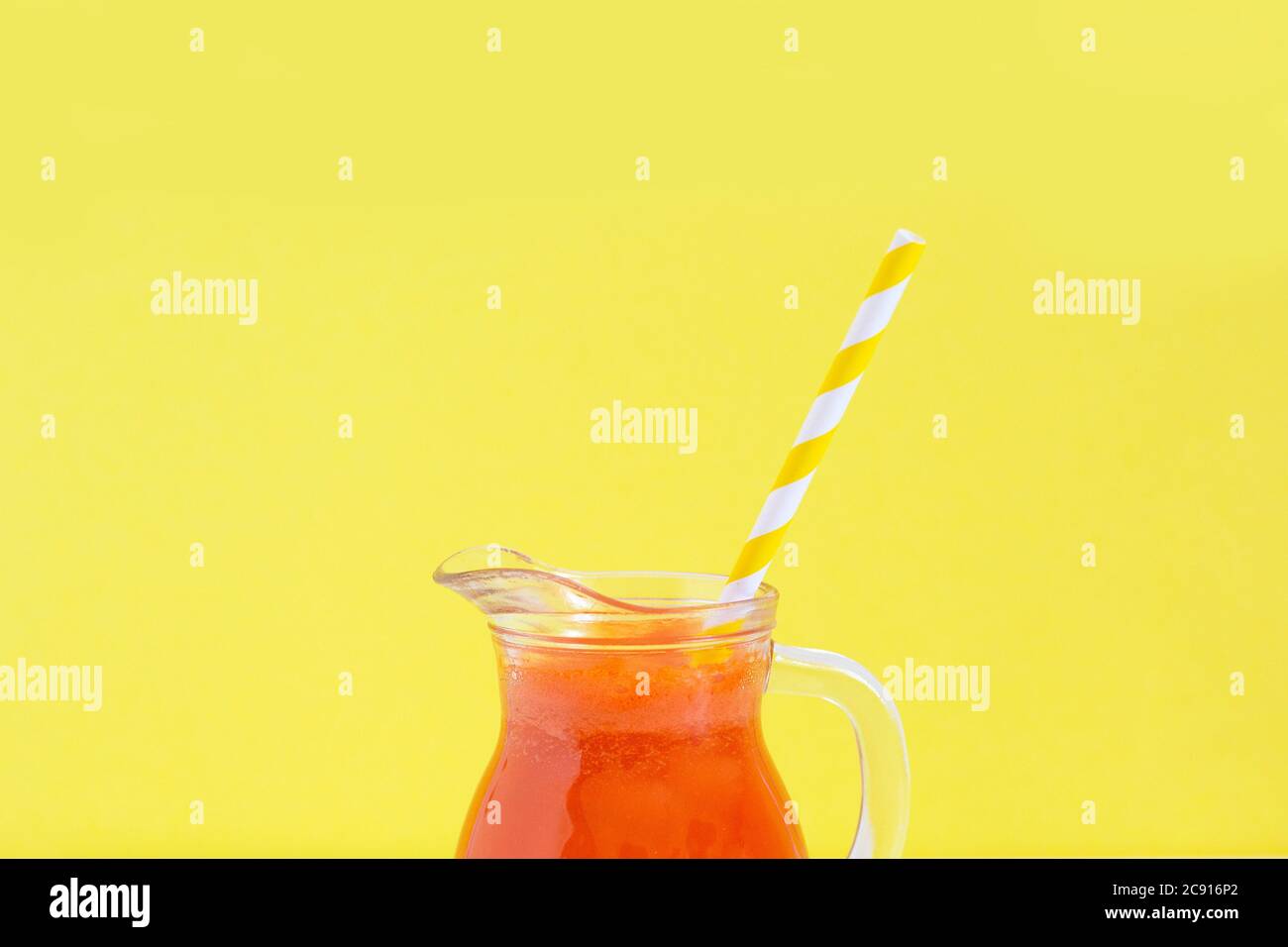 Carafe de jus de carotte avec tube à cocktail sur fond jaune. Alimentation saine de Detox, régime alcalin. Concept alimentaire d'été. Copier l'espace pour le texte. Banque D'Images