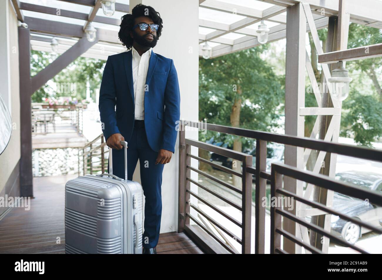 Homme noir en costume habillé avec une valise emballée entrant dans la ...