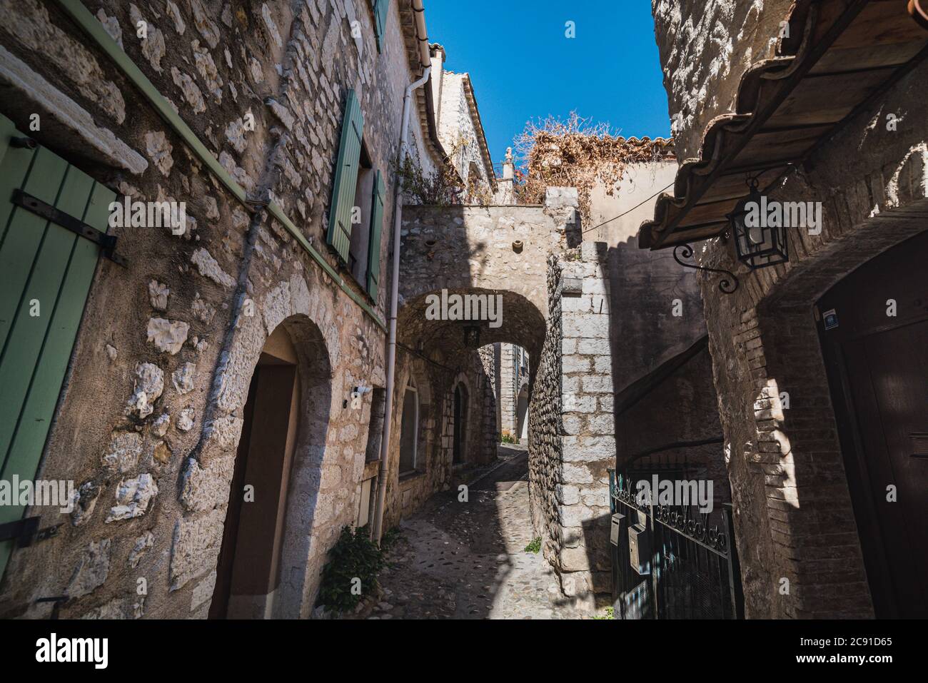 Une rue pavée avec une arche de pierre et de l'herbe sèche montre comment elle a dû ressembler dans un village médiéval - Saint Paul de Vence, France Banque D'Images