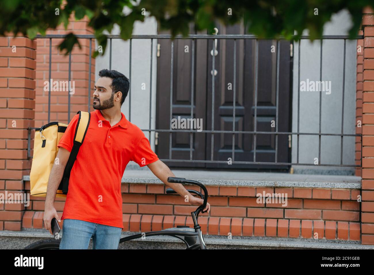Messagerie avec vélo, service de livraison de nourriture à la maison. Un homme avec un téléphone portable trouve l'adresse dans la ville Banque D'Images