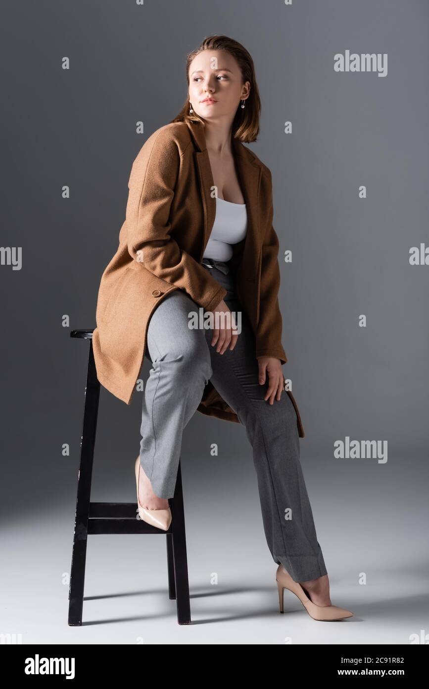 vue en longueur d'une fille en surpoids confiante et élégante, qui se pose  sur une chaise haute et qui donne sur le gris Photo Stock - Alamy