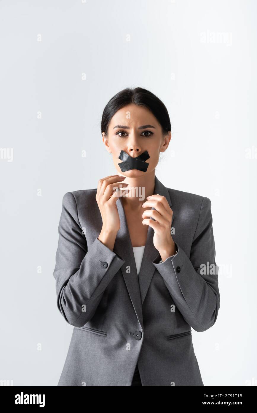 femme d'affaires avec bande scotch sur la bouche regardant la caméra isolée sur blanc, concept d'inégalité de genre Banque D'Images