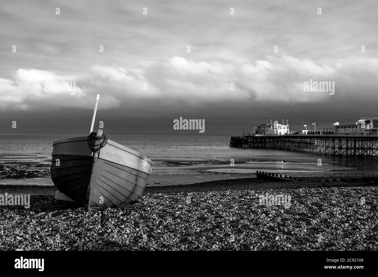Worthing Seafront West Sussex England UK - bateau de pêche rouge et bleu sur la plage avec Worthing Pier derrière au crépuscule Banque D'Images