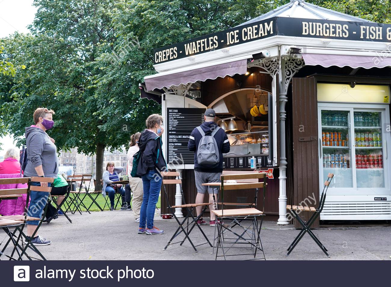 Edimbourg, Ecosse, Royaume-Uni. 28 juillet 2020. Depuis l'assouplissement des restrictions de verrouillage du coronavirus Covid-19, un nombre croissant de visiteurs commencent à se rassembler au café extérieur et aux tables dans les jardins East Princes Street Gardens. File d'attente à distance au kiosque du café. Crédit : Craig Brown/Alay Live News Banque D'Images