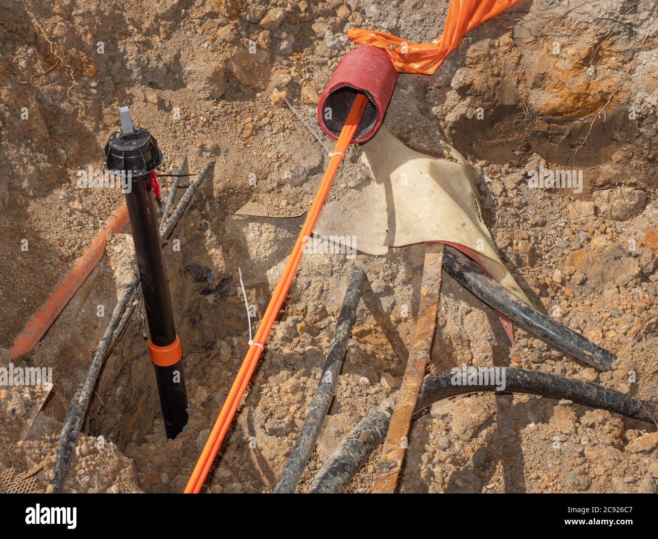 Tranchée de construction avec fils électriques. Travaux routiers pour l'installation de câbles à fibres optiques pour les télécommunications. Banque D'Images