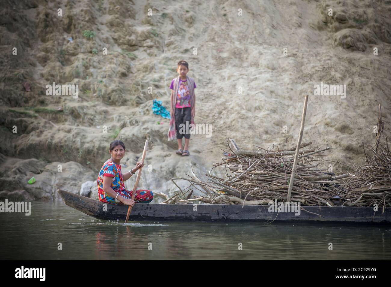 Chittagong, Bangladesh, 25 février 2016 : femme en bateau-bateau sur une rivière voyageant avec une charge de bois de chauffage dans les zones rurales du Bangladesh Banque D'Images