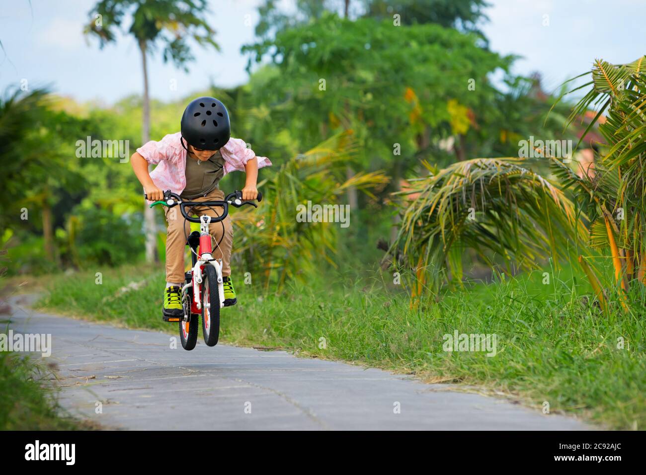 Randonnée à vélo. Jeune rider enfant dans un casque et des lunettes de soleil à vélo. Un enfant heureux s'amuse sur un sentier vide. Vie familiale active, sport, o Banque D'Images