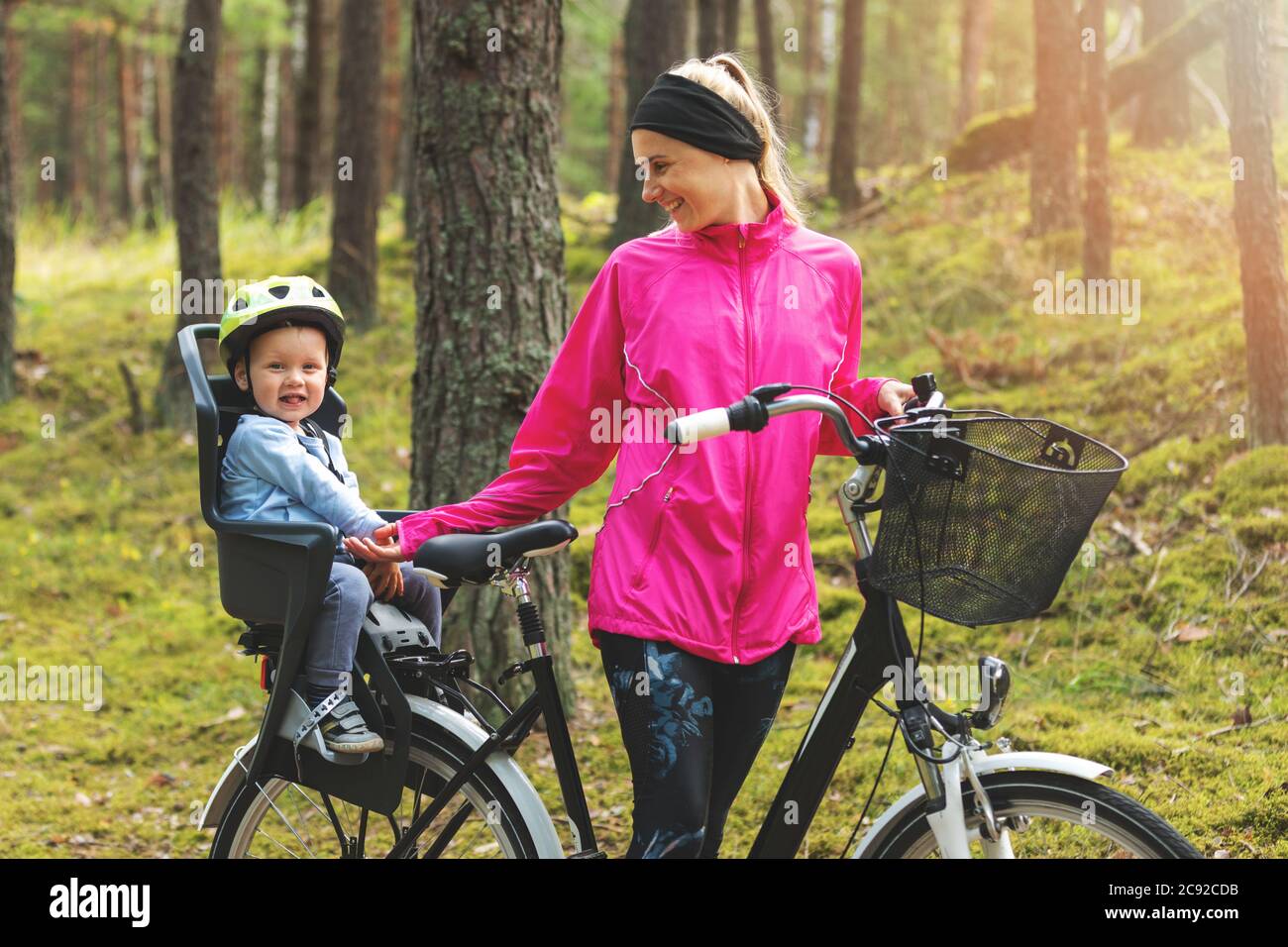 mère heureuse avec son fils en vélo siège enfant vélo sur la forêt piste Banque D'Images