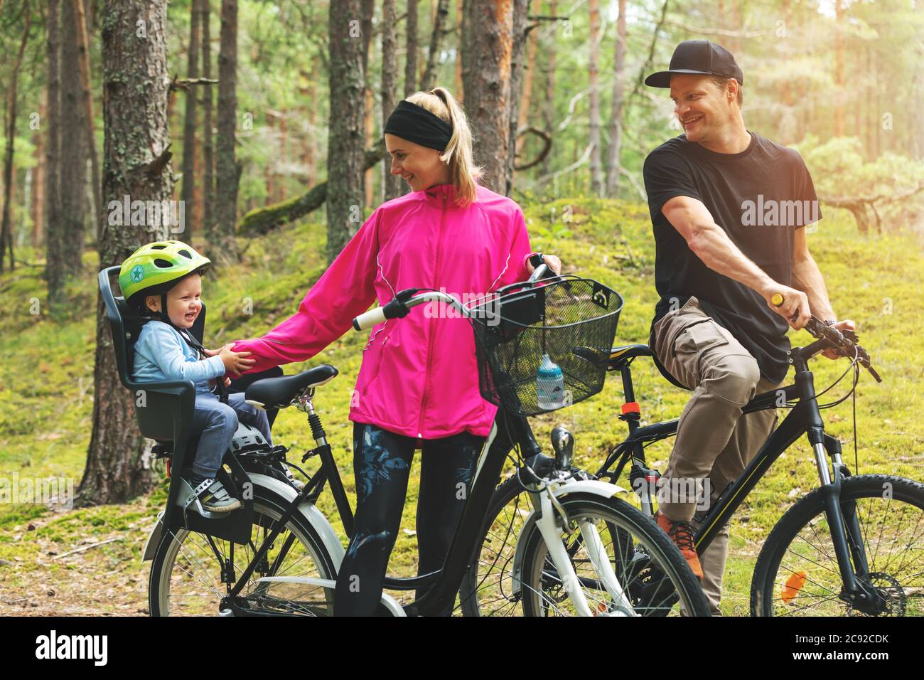 jeune famille heureux vélo dans la forêt avec enfant dans le vélo siège enfant. sports actifs loisirs en plein air Banque D'Images