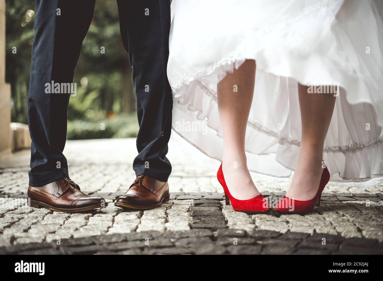 Jambes de la mariée et du marié pliées vers l'intérieur. Drôle et conceptuel. Banque D'Images