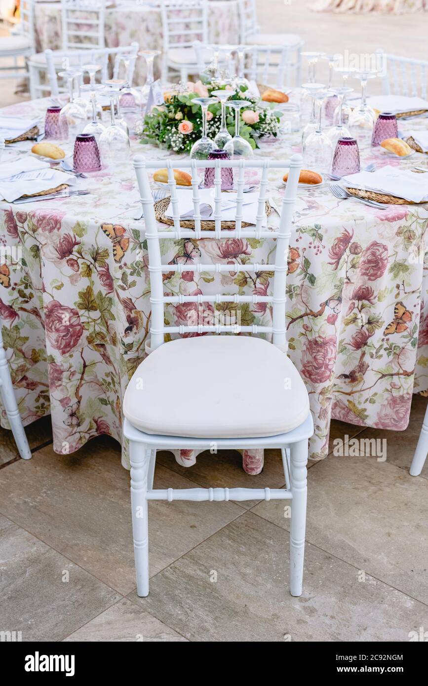 Coutellerie en cristal et nappe fleurie sur une table de mariage décorée  avec goût et chaise blanche Photo Stock - Alamy