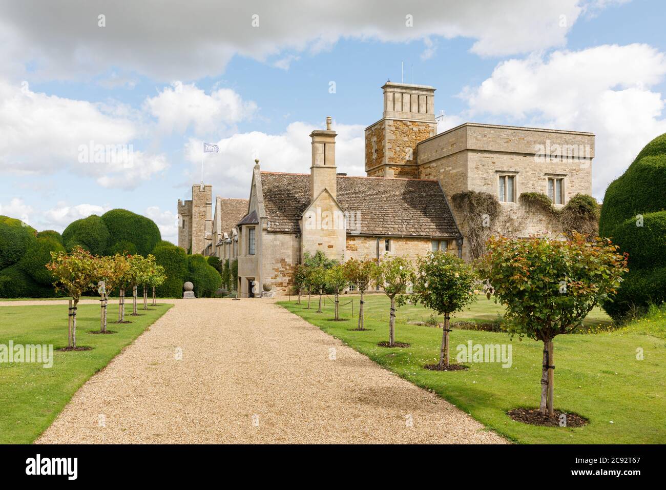 Rockingham, Northamptonshire, Royaume-Uni - 28/07/20: Des rosiers bordent un chemin menant aux bâtiments en pierre du château de Rockingham, autrefois château royal. Banque D'Images