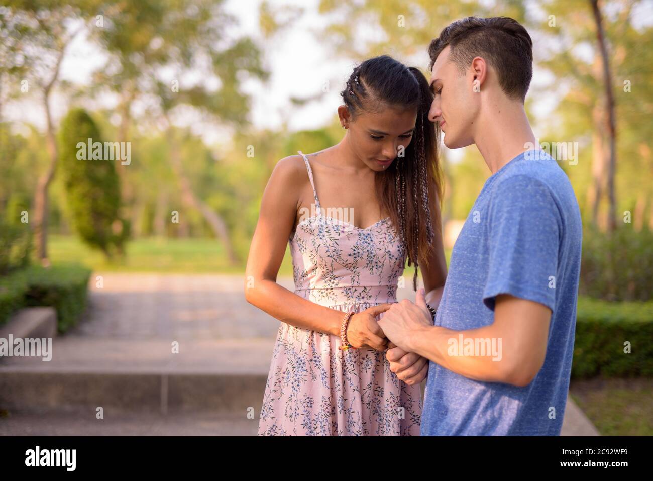 Portrait d'un jeune couple multiethnique se relaxant ensemble au parc Banque D'Images