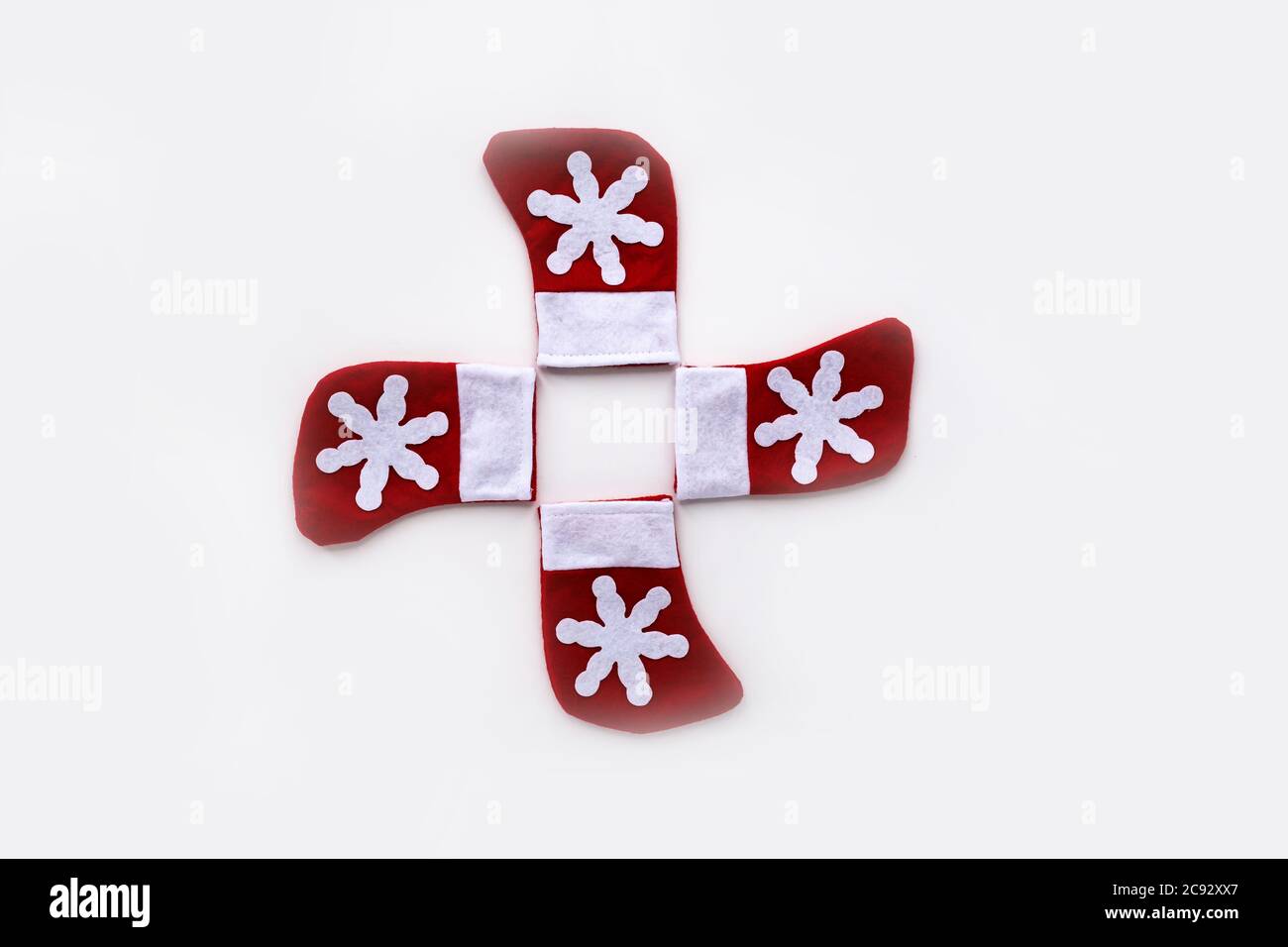 Composition circulaire de 4 jouets rouges avec bottes en flocon de neige pour des cadeaux de Noël sur fond blanc. Pose à plat Banque D'Images