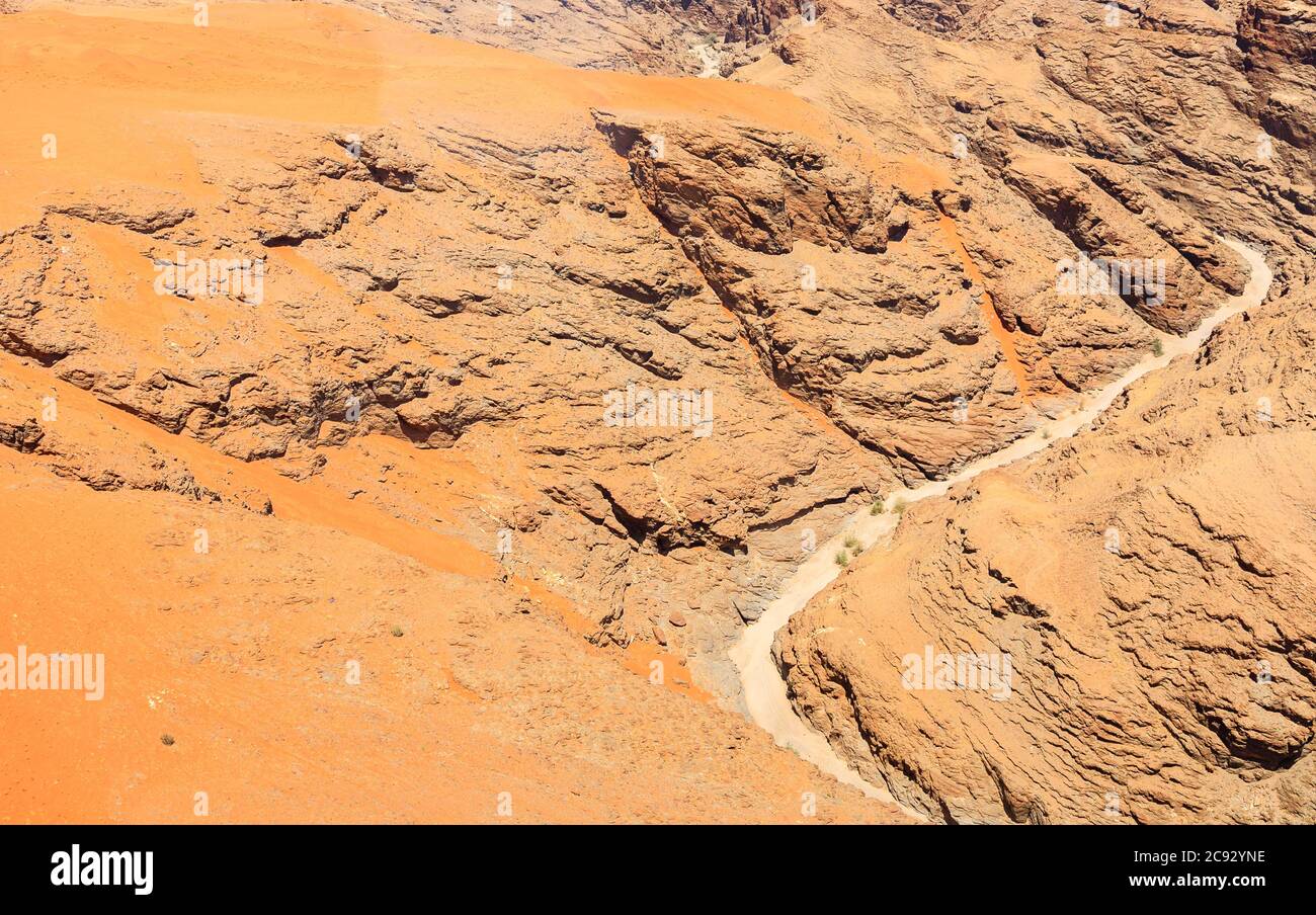 Cours d'eau de lit de rivière séché typique dans un terrain montagneux sombre et aride du désert de Namib avec du sable ocre sur une roche stratifiée sur la côte de Skeleton, Namibie, Afrique du Sud-Ouest Banque D'Images