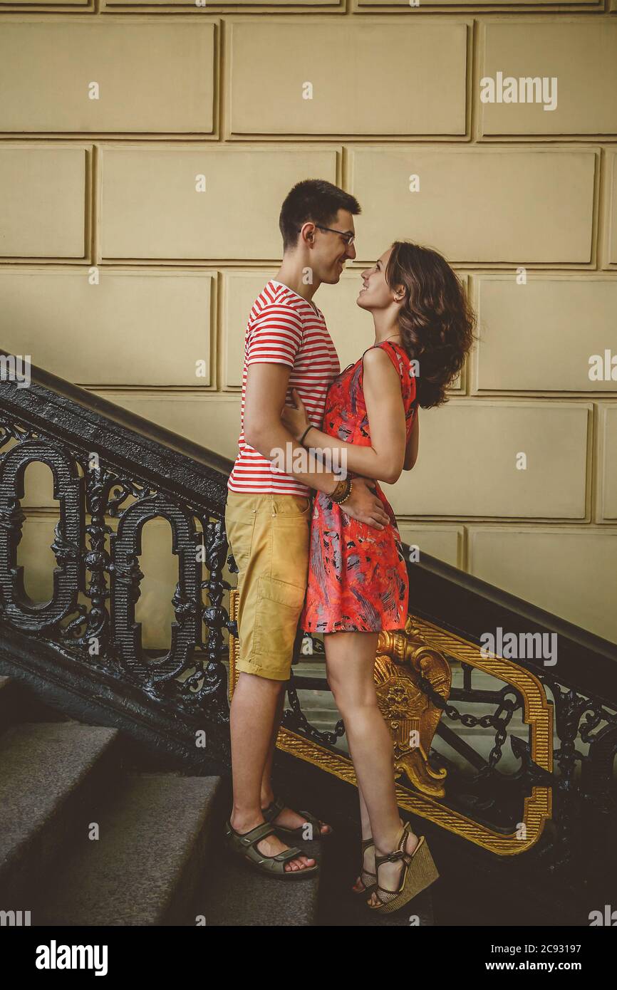 Beau jeune couple à l'extérieur dans des escaliers vintage souriant et embrassant, regardant les uns les autres Banque D'Images