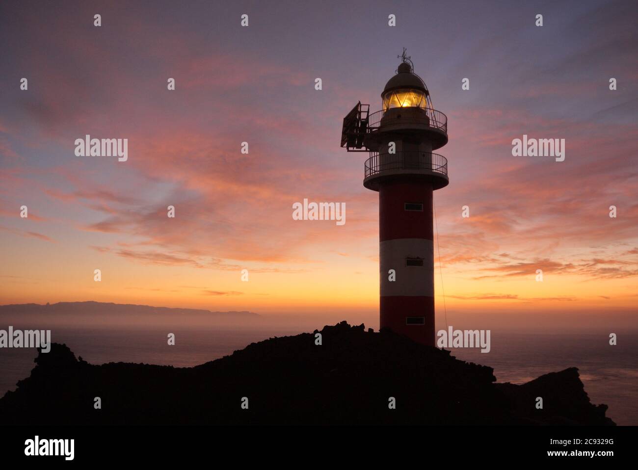 Buenavista del Norte, Santa Cruz de Tenerife/Espagne; 10 octobre 2011. Coucher de soleil au phare de Punta de Teno, avec l'île de la Gomera dans l'arrière-gro Banque D'Images