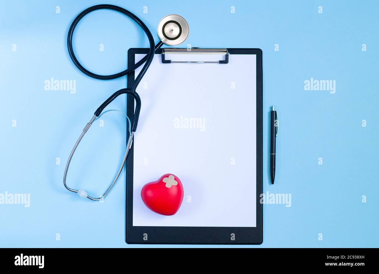 Vue de dessus de la table du bureau du médecin avec stéthoscope, cœur rouge, stylo et papier vierge sur le presse-papiers. Concept des maladies de cardiologie Banque D'Images