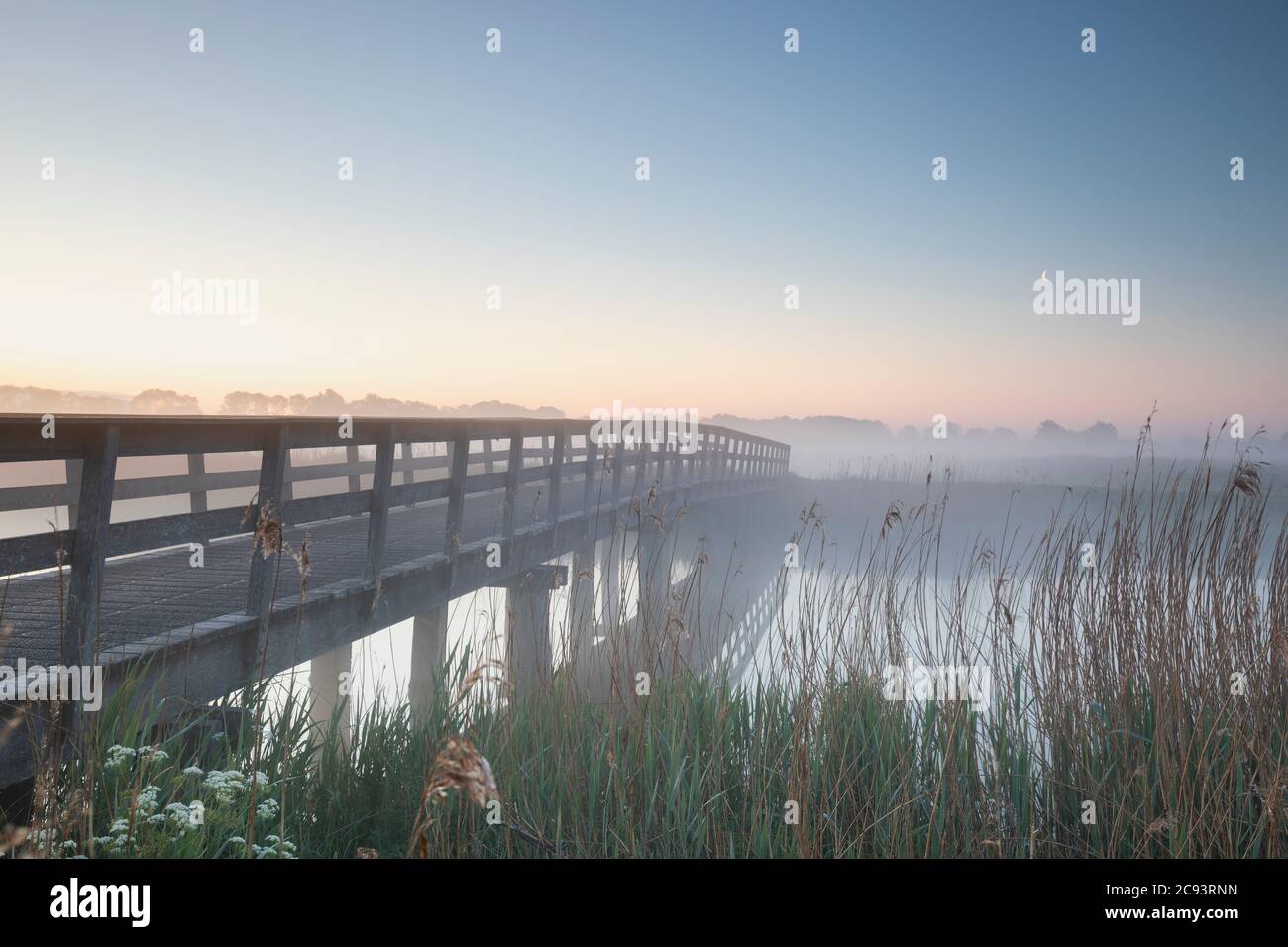 lever de soleil brumeux et serein au-dessus du pont et de la rivière avec la lune Banque D'Images