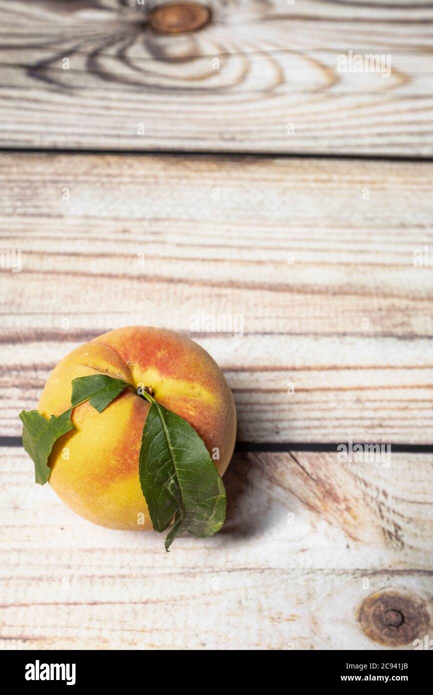 Fruit de pêche mûr avec feuille verte sur fond de bois Banque D'Images