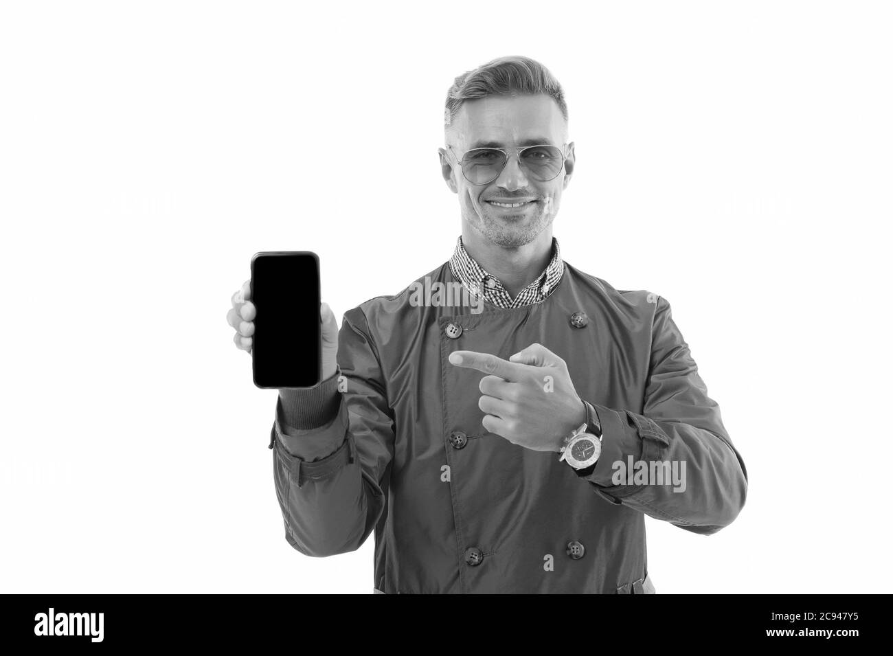 Aimez-vous ce téléphone ? Homme d'affaires pointe le doigt sur le téléphone portable. Un homme charmant tient le téléphone isolé sur blanc. Communication d'entreprise. 3G. 4G. Appareil mobile. Vous n'êtes jamais seul avec un téléphone portable. Banque D'Images