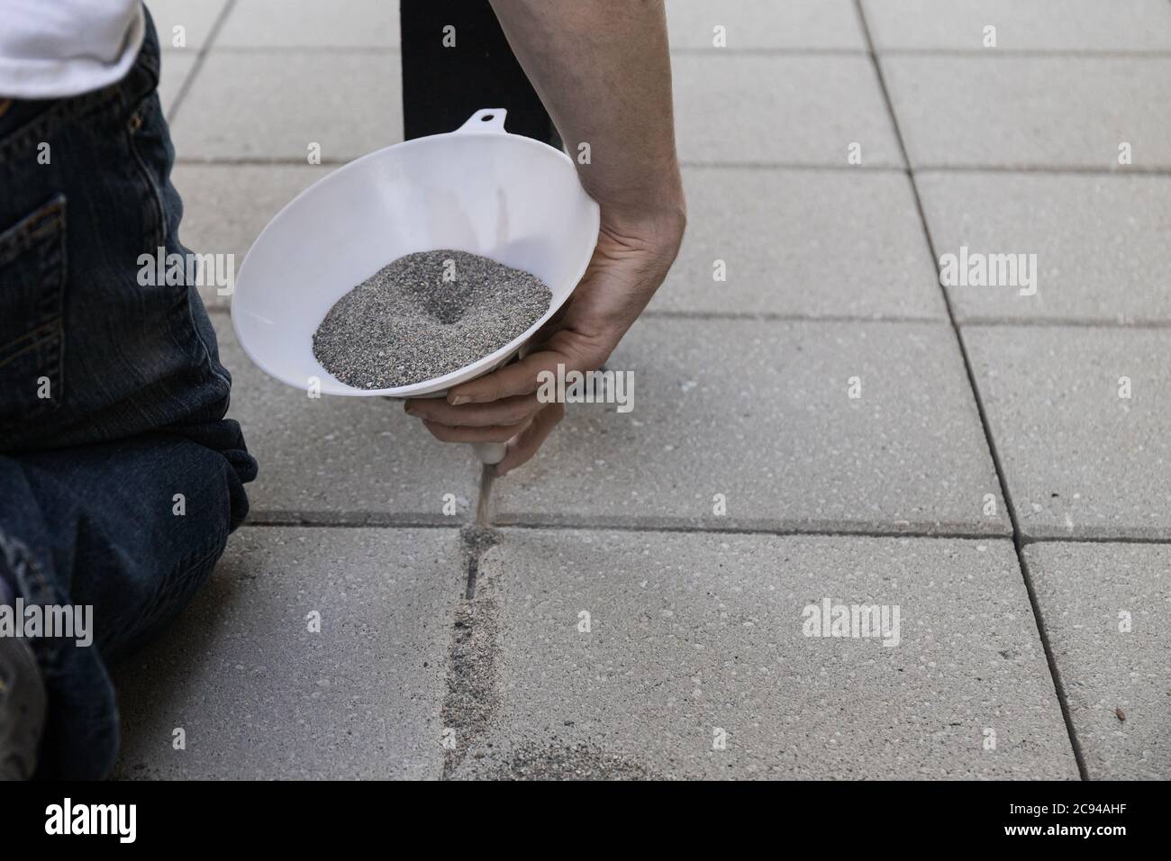 Verser le sable de jointing dans l'installation du patio du finisseur Banque D'Images