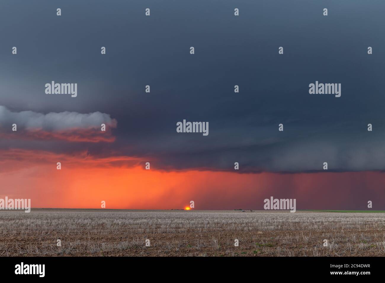 Une grande tempête traverse les grandes plaines tandis que le soleil se couche derrière et que la pluie coule le long de l'horizon. Banque D'Images