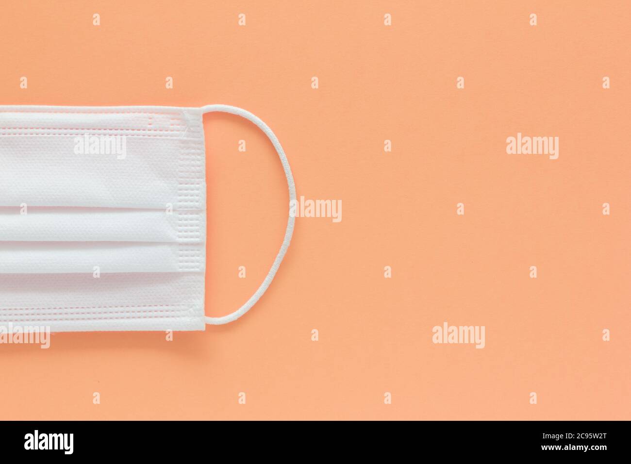 Photo d'un gros plan d'un masque de visage isolé sur un fond de saumon et un espace de copie sur la droite Banque D'Images Photo d'un gros plan d'un masque de visage isolé sur un fond de saumon et un espace de copie sur la droite Banque D'Images