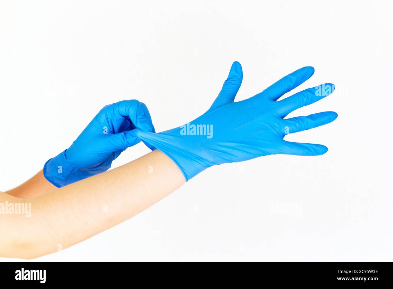 Photo d'une femme mettant des gants en latex bleu sur un fond blanc Banque D'Images