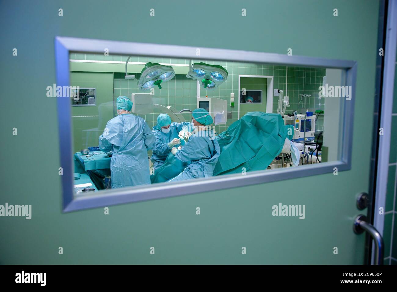 Essen, Rhénanie-du-Nord-Westphalie, Allemagne - Hôpital. Vue dans une salle d'opération à travers une fenêtre. Une équipe chirurgicale travaille sur une opération au pied. - Banque D'Images