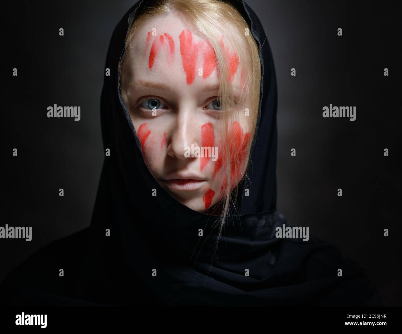 Portrait de jeune femme avec de la peinture sur son visage sur fond sombre. Banque D'Images