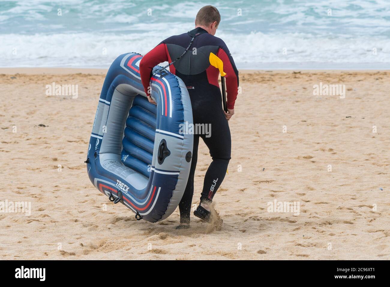 Un holidaymaker portant un canot pneumatique sur Fistral; plage à Newquay en Cornouailles. Banque D'Images