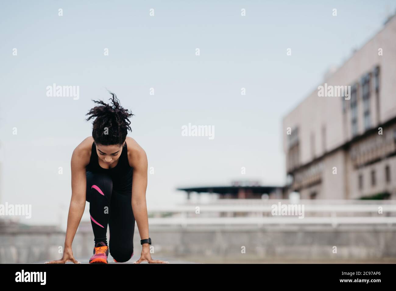 Entraînement avant les événements sportifs. Une jeune fille concentrée dans des vêtements de sport avec des supports de tracker de forme physique au début Banque D'Images