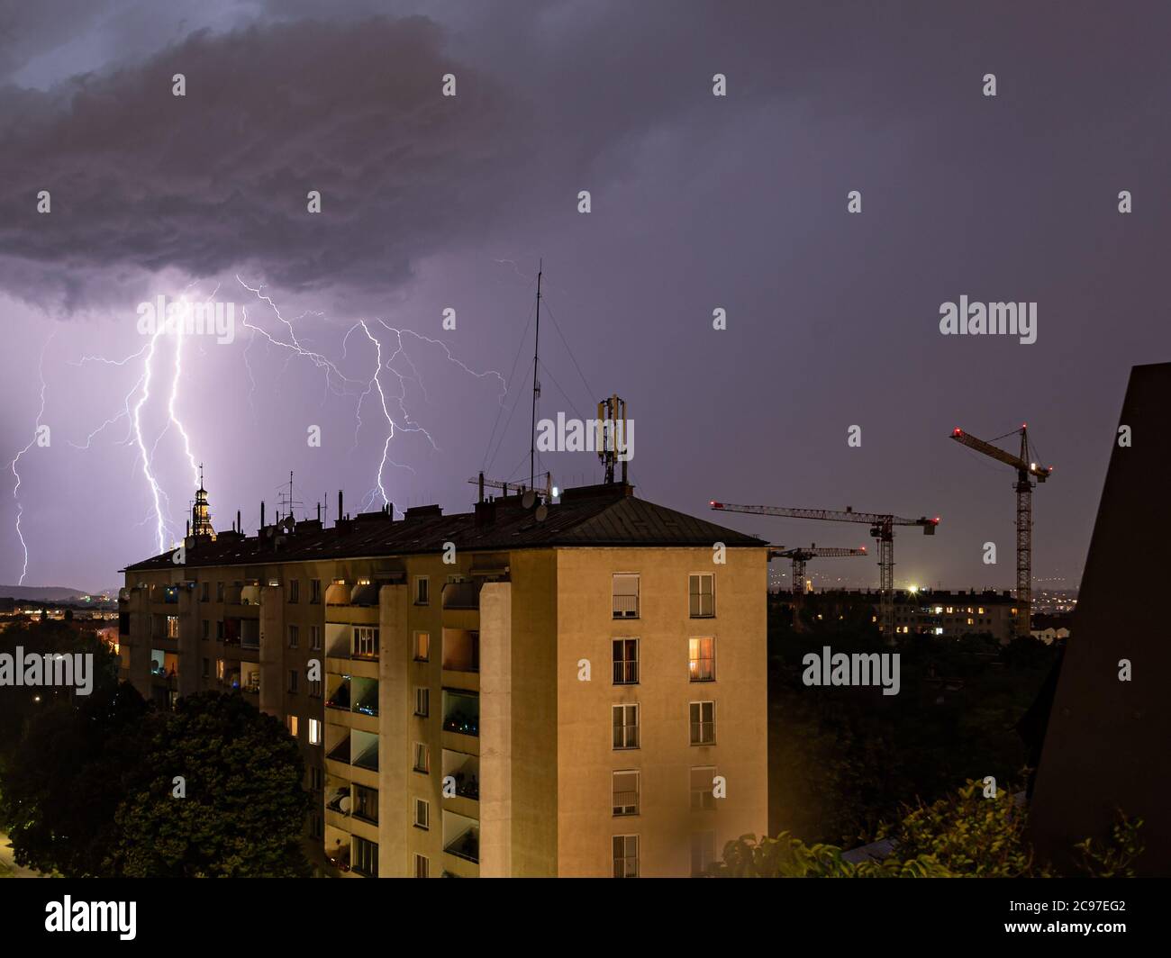 Violent orage d'été avec un éclair énorme sur la ville de Wienerberg à Vienne avec des grues de construction sur le côté droit de la photo Banque D'Images