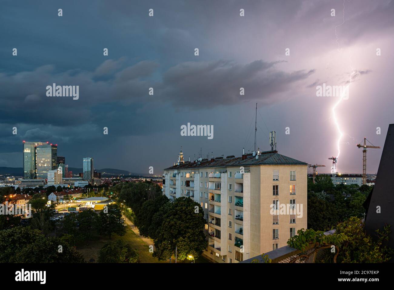 Violent orage d'été avec un éclair énorme sur la ville de Wienerberg à Vienne avec des grues de construction sur le côté droit de la photo Banque D'Images