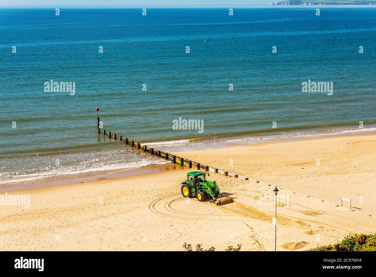 Un tracteur déplaçant du sable sur une plage anglaise par une journée ensoleillée en arrière-plan magnifique océan, industrie côtière Banque D'Images
