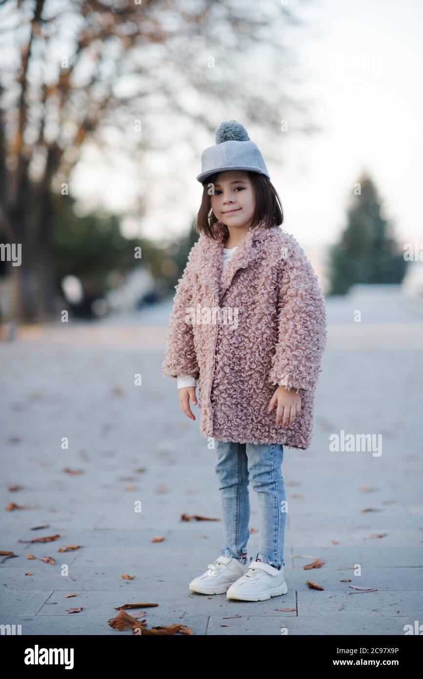 Jolie petite fille de 5-6 ans portant un manteau d'hiver et un chapeau  élégant posant dans le parc à l'extérieur. Saison d'automne. Enfance.  Bonheur Photo Stock - Alamy