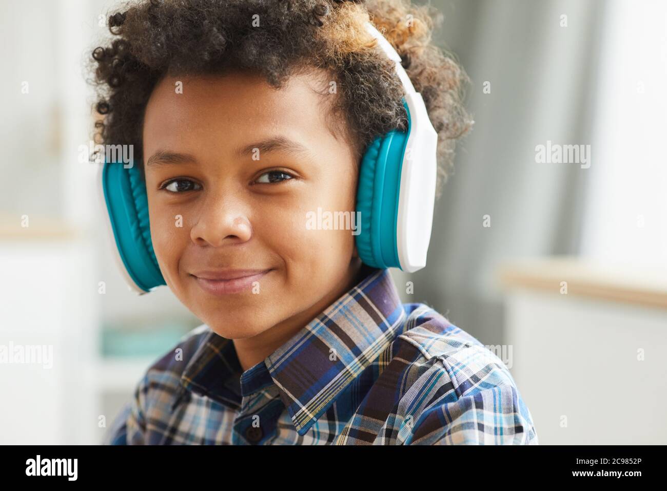 Portrait d'un petit garçon africain dans un casque souriant à l'appareil photo tout en étant assis à la maison Banque D'Images