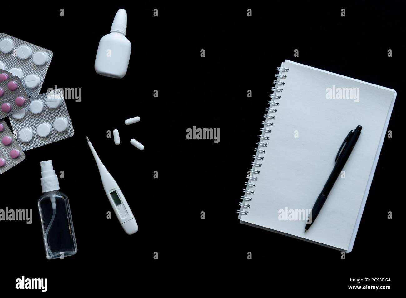 vue de dessus du thermomètre, des pilules et du carnet sur fond noir Banque D'Images