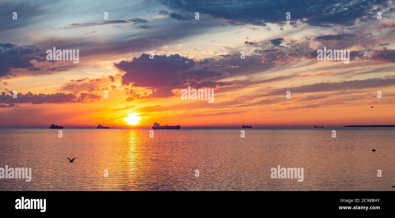 Silhouette de navires sur fond à la mer au beau coucher du soleil Banque D'Images