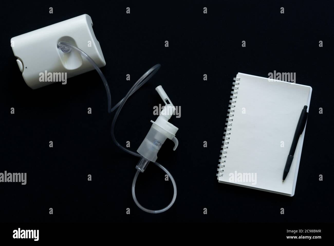 vue de dessus du nébuliseur et du bloc-notes sur fond noir Banque D'Images