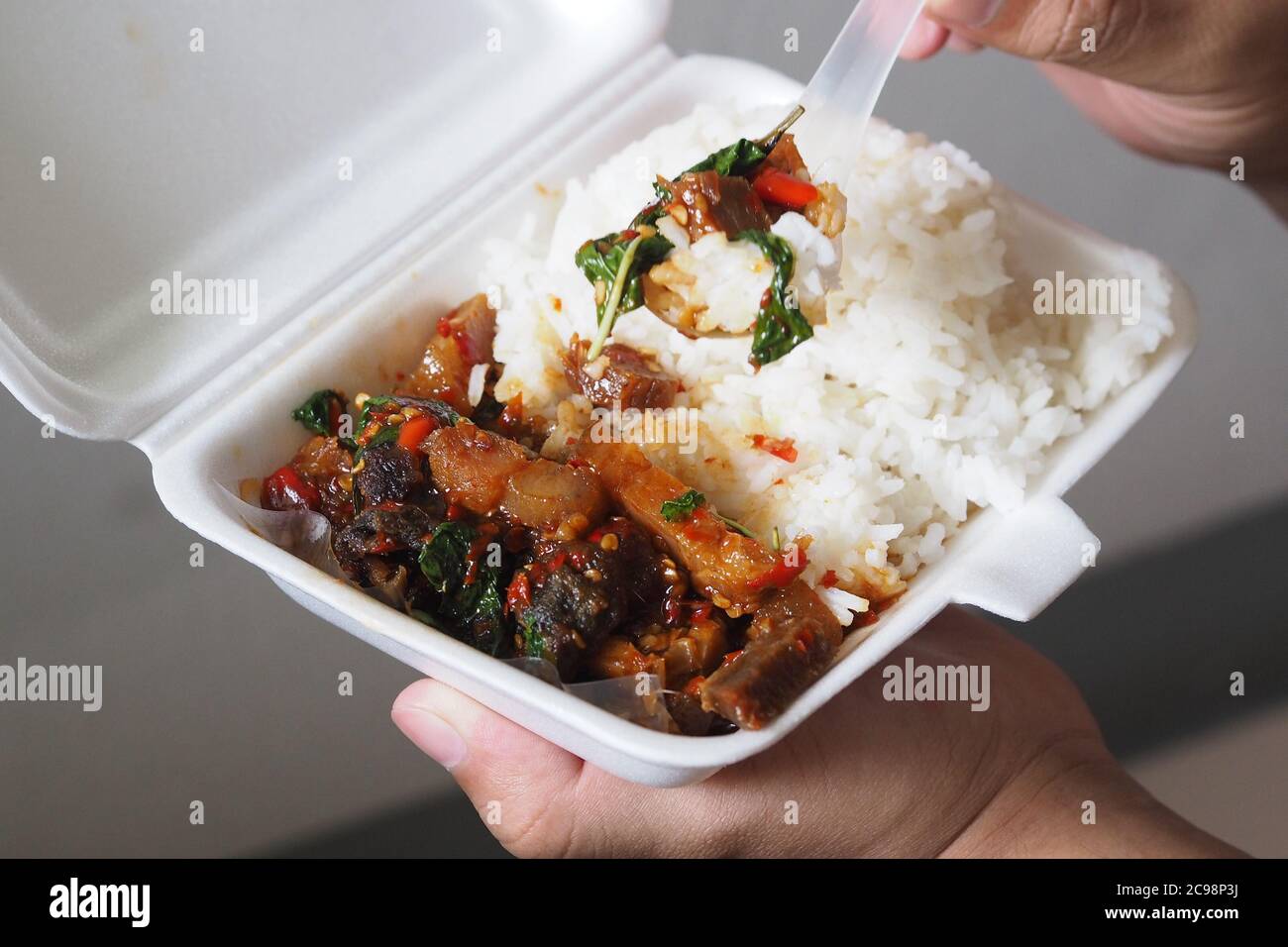 Porc croustillant sauté aux piments et feuilles de basilic Riz dans une boîte en mousse pour emporter à la maison Banque D'Images