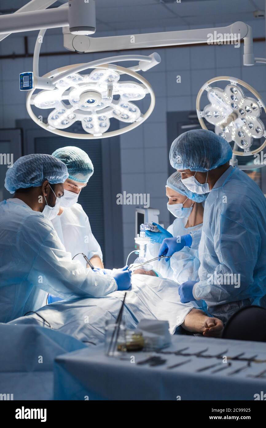 La chirurgie d'urgence. Chirurgiens intelligents smart professionnel debout près du patient et l'exécution d'une opération lors de l'enregistrement de sa vie. Trea professionnel Banque D'Images